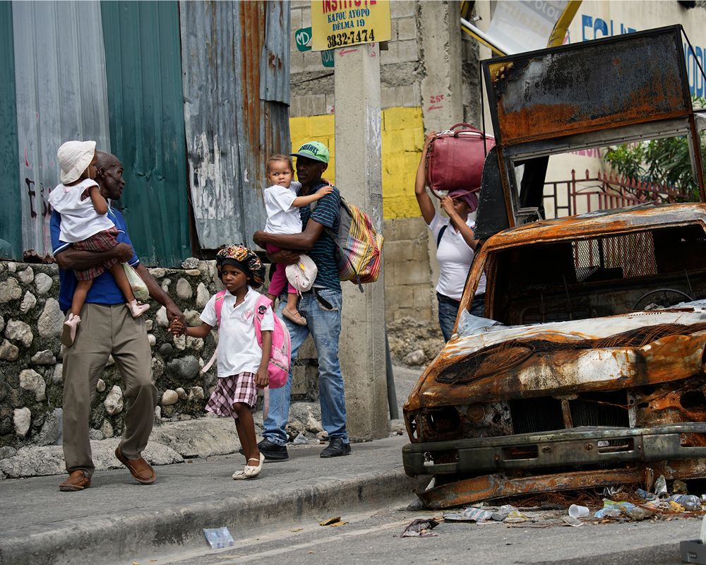 Family pass a burnt-out car 